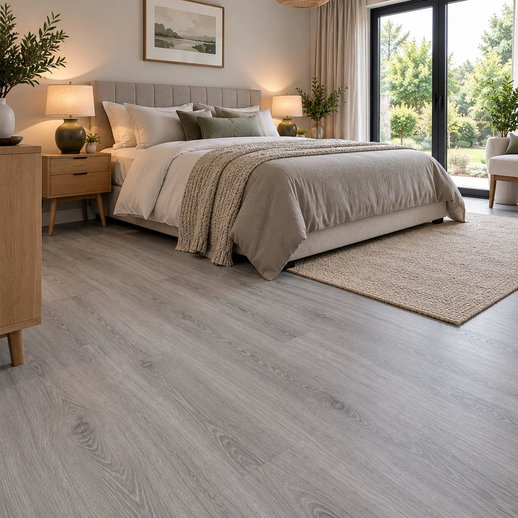 Light grey wood effect vinyl plank flooring in a neutral bedroom with an oak sideboard and textured rug