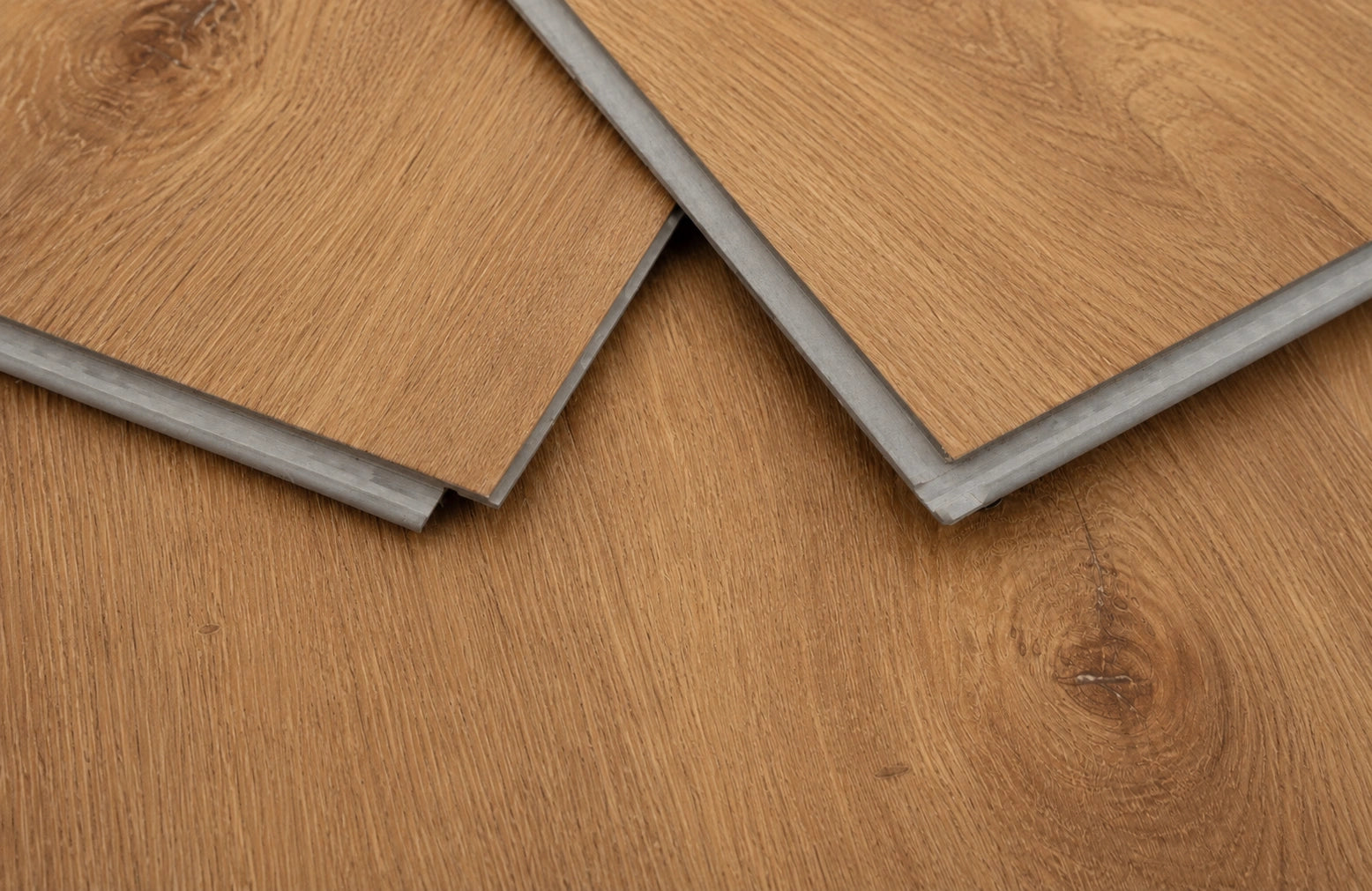 Close-up of Harvest Oak SPC click planks showing the rigid core profile and warm natural oak wood grain finish