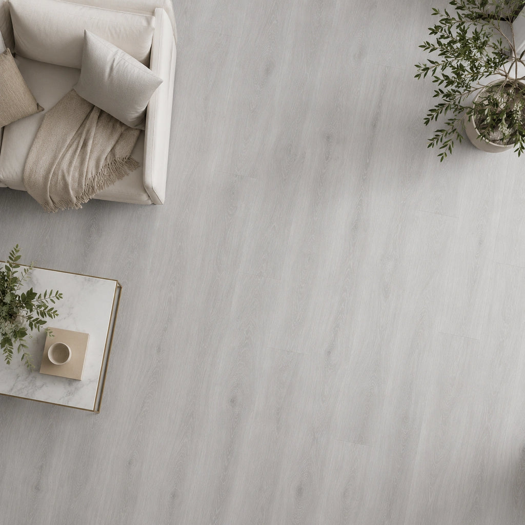 Light grey oak SPC flooring in a living room, styled with a cream sofa, cushions, throw, marble coffee table and potted plants