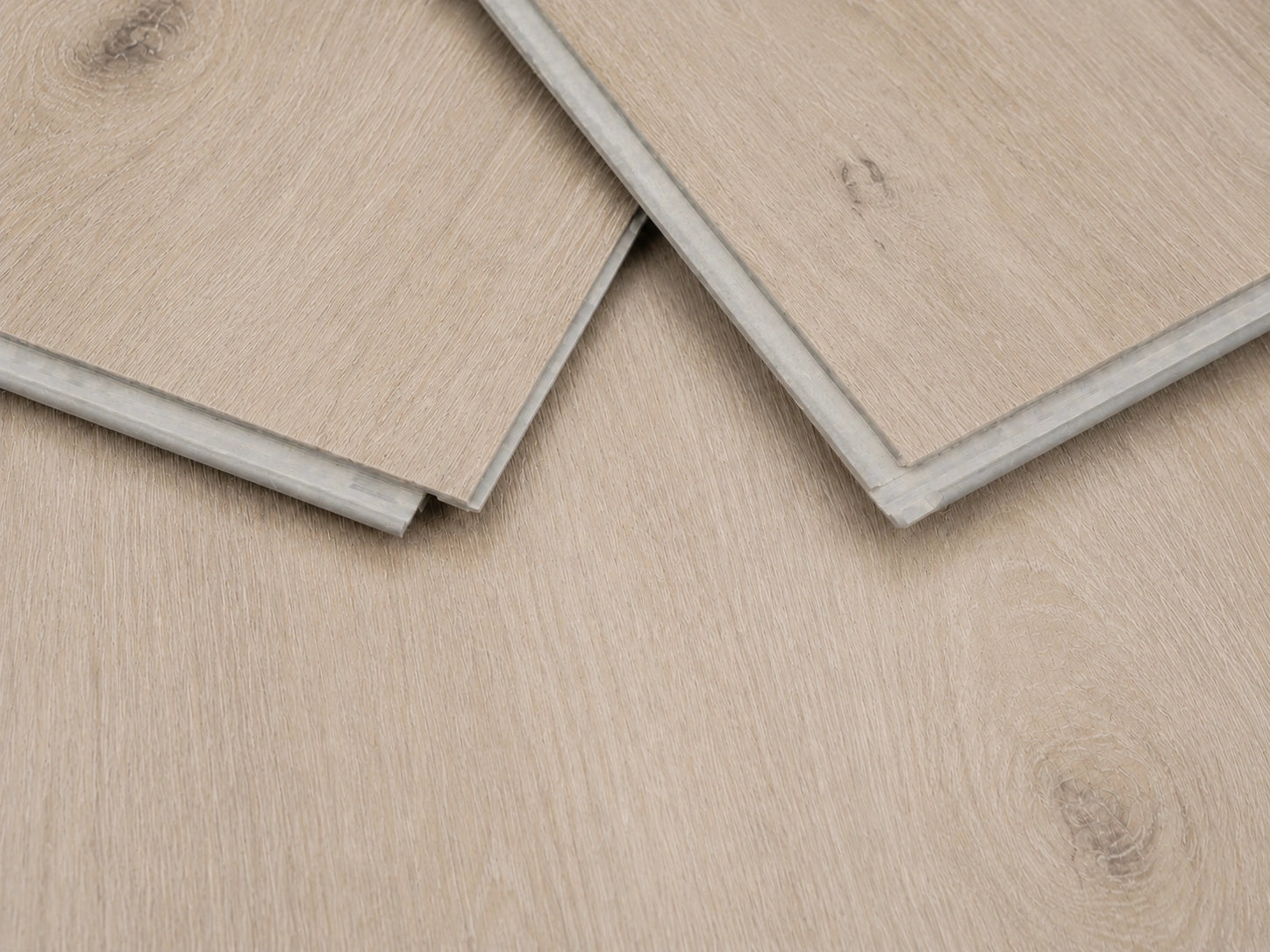 Close-up of Natural Pine Oak SPC click-lock planks showing the rigid core profile, tongue and groove joint and pale linen-toned oak surface finish