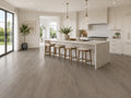 Seasoned Oak SPC flooring in a bright open-plan kitchen with white marble island, gold pendant lighting, timber bar stools and garden views